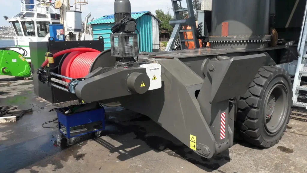 BM Makina KATO MKT Geniş Sarım Kablo Toplama Tamburu, liman tipi lastik tekerlekli mobil vinç üzerinde yandan görünüm, kırmızı güç kablosu sarılı halde.